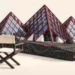 Illustration de la Cité du Volcan réinterprétée en maquette sur un socle de roche volcanique, avec un fauteuil vide symbolisant le poste de direction à pourvoir.
