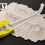 Sous le cartouche « ACTE II ? », un gilet jaune plié repose sur une silhouette de La Réunion en relief ; sa bande réfléchissante devient un chemin qui se divise en deux directions.