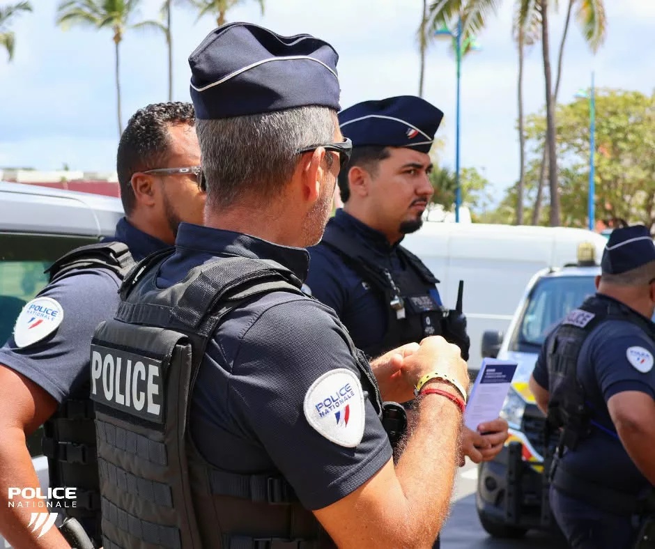 Policiers nationaux en uniforme à La Réunion, avec un document d’information tenu par l’un des agents.