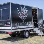 Le camion de Kouler Lo Ker, portant le nom et le logo de l’association, avec sa porte ouverte et un escalier d’accès.
