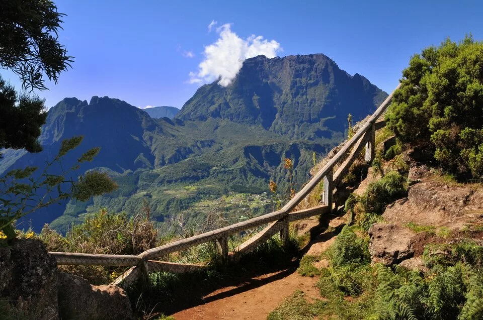 Panorama sur le cirque de Mafate depuis le Maïdo, avec un chemin et une rambarde en bois au premier plan.