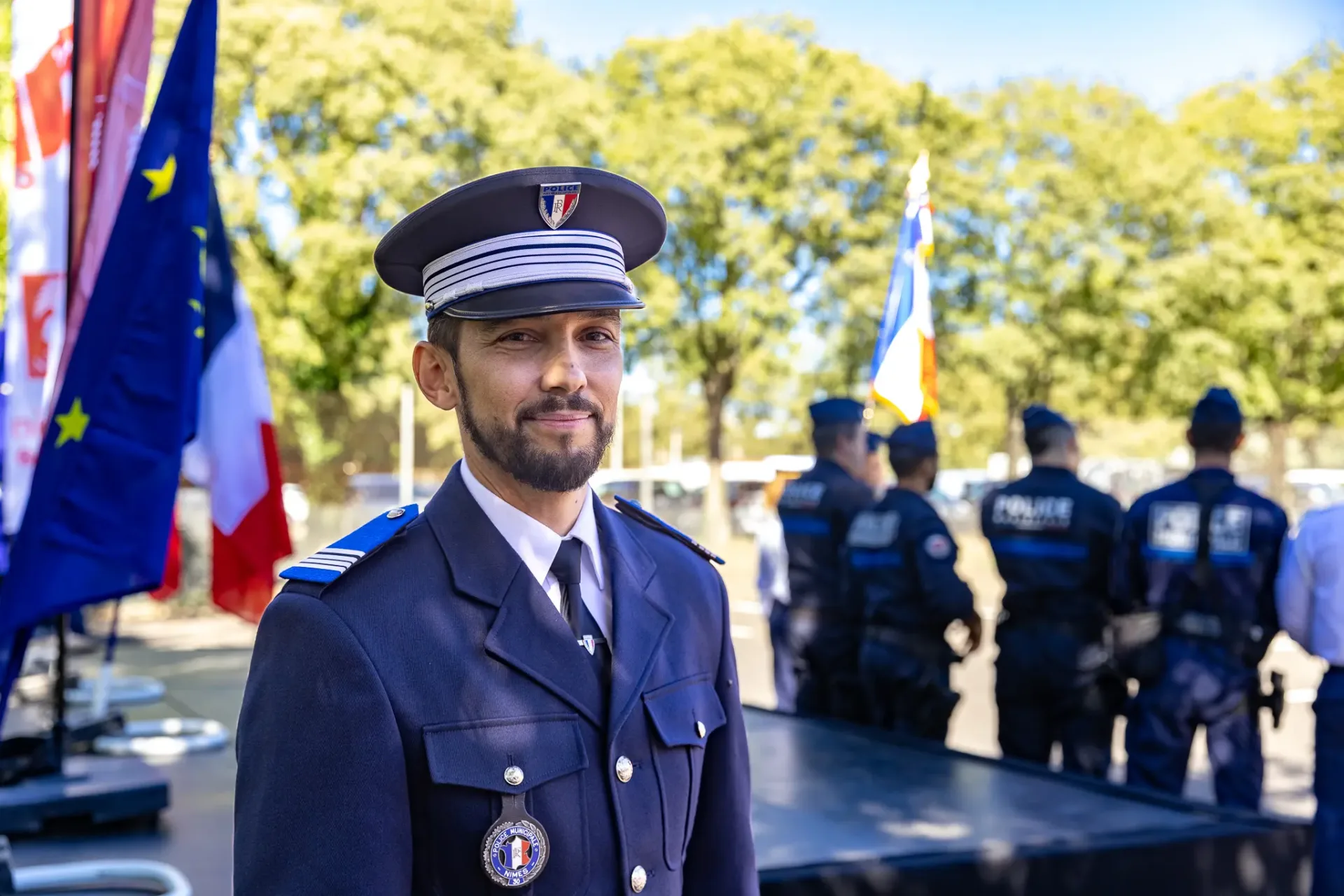 Laurent Barret en uniforme de police municipale, devant des drapeaux et plusieurs policiers à Nîmes.