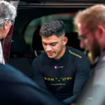 Rehane Gany en combinaison de pilote, assis au milieu de son entourage.