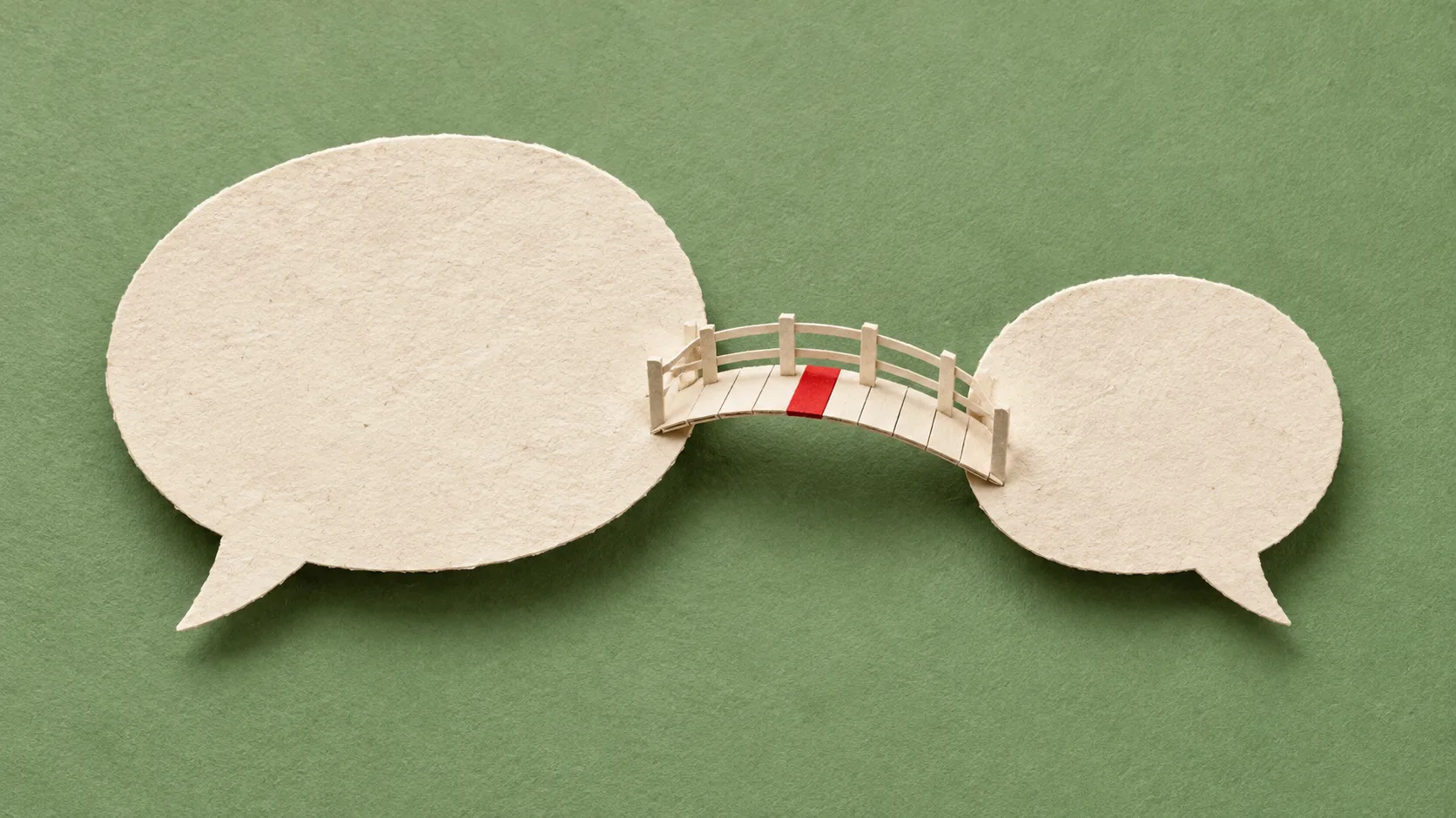 Deux bulles de dialogue en papier ivoire reliées par une petite passerelle, sur fond vert sauge avec un accent rouge.